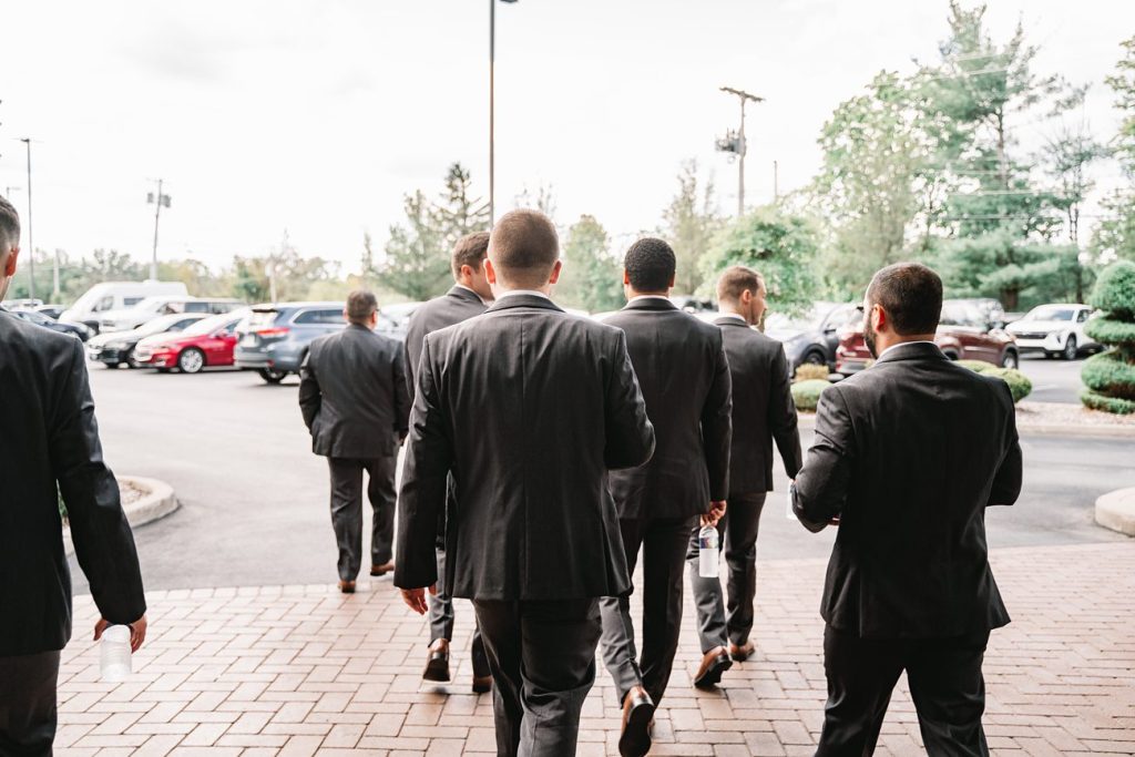 a group of men in suits walking on a brick sidewalk