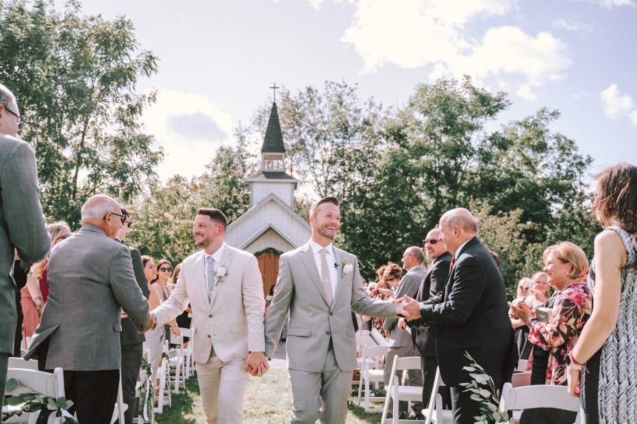 Grooms holding hands after their Upstate New York barn wedding ceremony