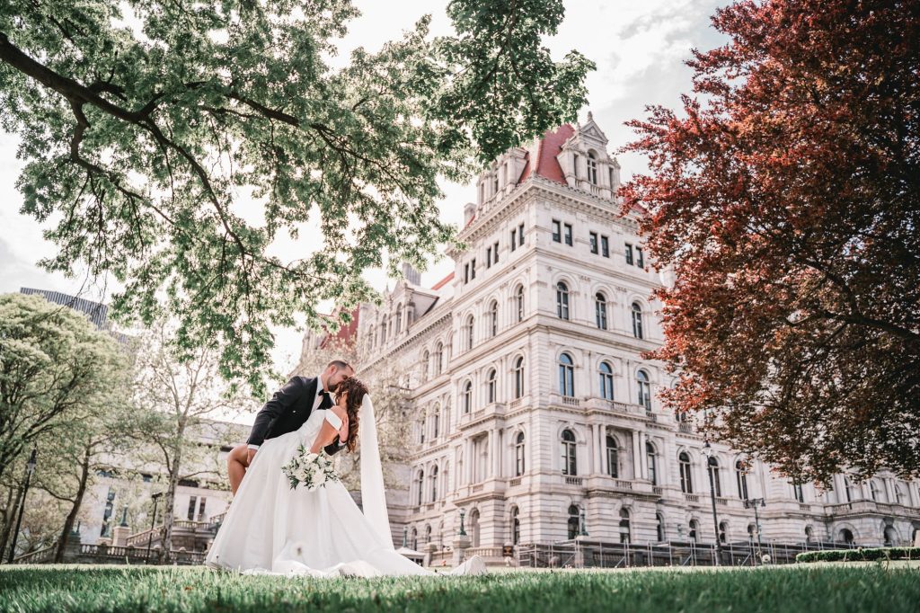 a bride and groom kissing in front of building for their upstate NY wedding